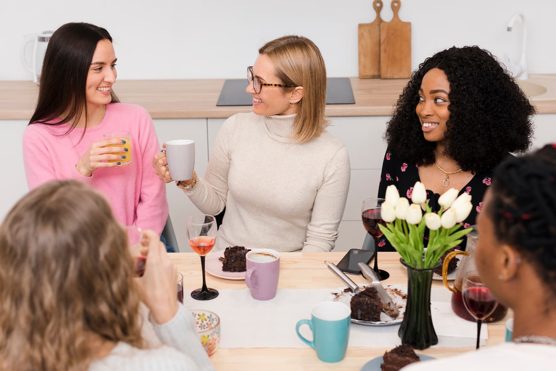 A group of women enjoying conversation and drinks together around a table